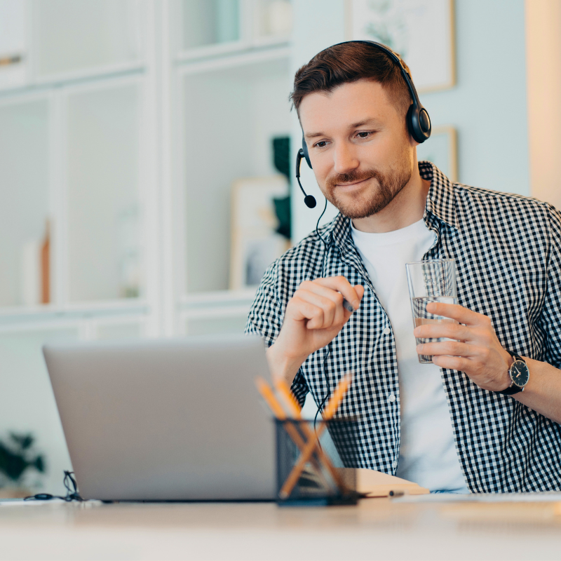 Person mit Headset vor einem Laptop nimmt an einem Online-Webinar teil